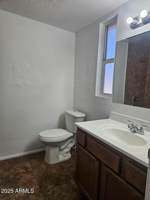 bathroom with toilet, vanity, a textured ceiling, and a textured wall