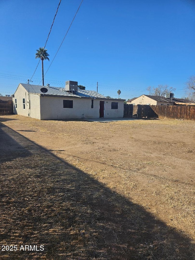 rear view of house featuring cooling unit and fence