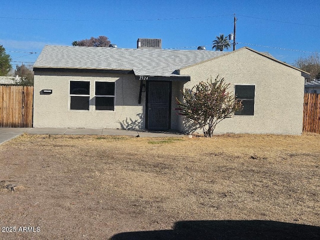 ranch-style house featuring central AC, fence, and stucco siding