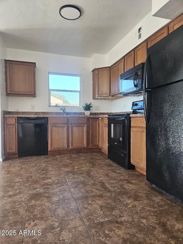 kitchen with visible vents, brown cabinetry, a textured ceiling, black appliances, and a sink