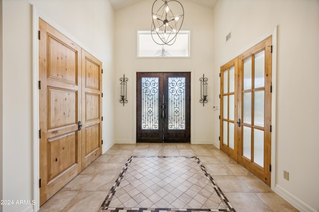 foyer entrance featuring french doors, light tile patterned flooring, a chandelier, and high vaulted ceiling