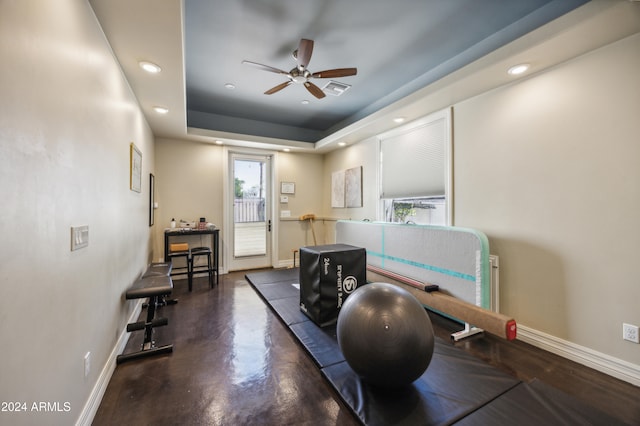 exercise area with ceiling fan and a raised ceiling