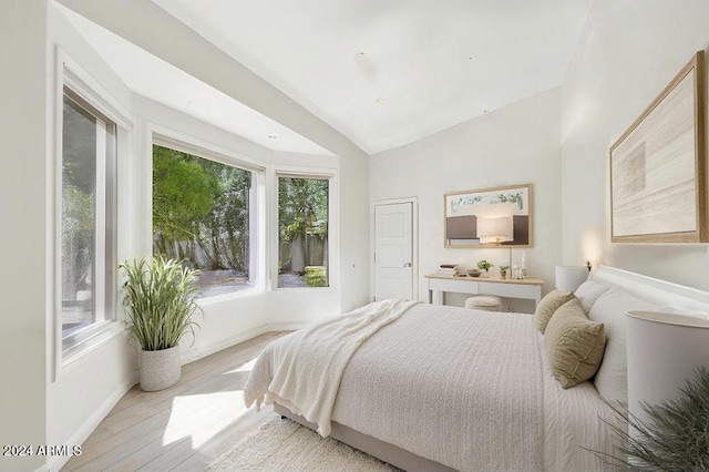 bedroom with light hardwood / wood-style floors and lofted ceiling