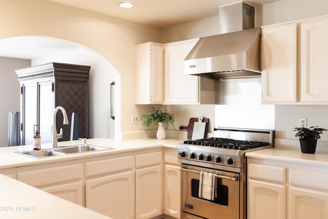 kitchen with premium range, sink, and wall chimney exhaust hood