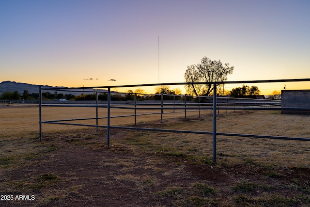 yard at dusk featuring a rural view and a mountain view