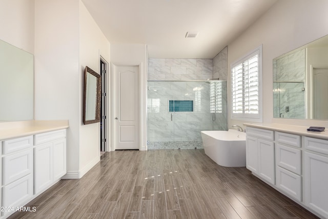 bathroom with vanity, wood-type flooring, and plus walk in shower