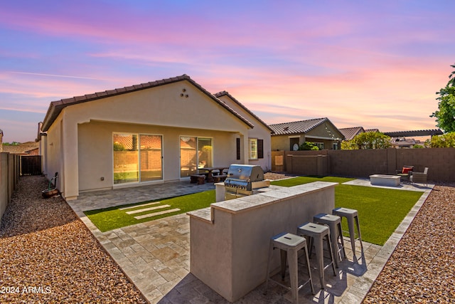 back house at dusk featuring an outdoor living space, an outdoor kitchen, a patio area, and an outdoor bar