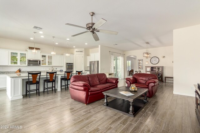 living room featuring ceiling fan and light hardwood / wood-style floors