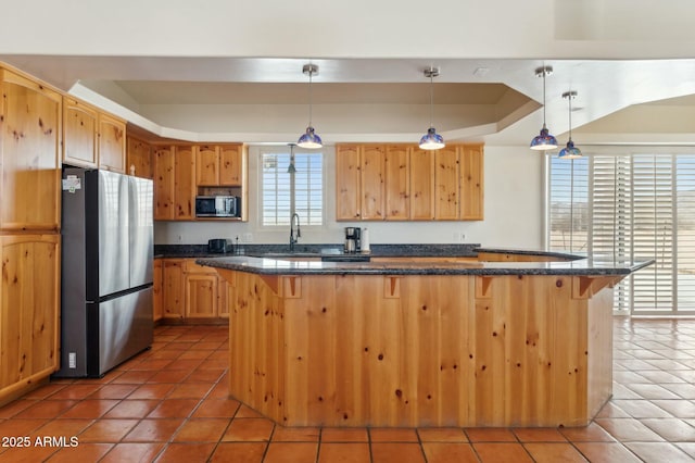 kitchen featuring light brown cabinetry, appliances with stainless steel finishes, light tile patterned floors, and a breakfast bar area