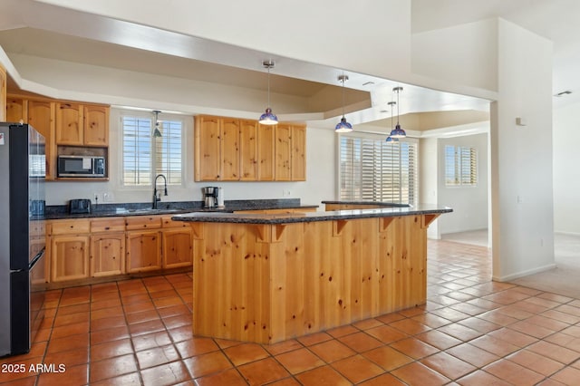 kitchen featuring a center island, decorative light fixtures, a sink, a kitchen bar, and stainless steel appliances