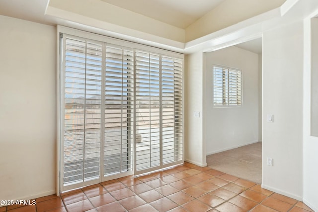 carpeted empty room with tile patterned floors and baseboards