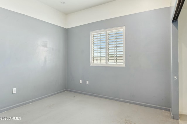 spare room featuring baseboards and concrete flooring