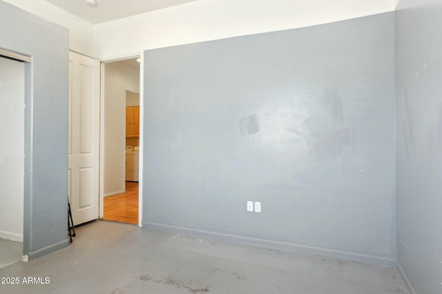 unfurnished room with concrete floors, washer / clothes dryer, and baseboards
