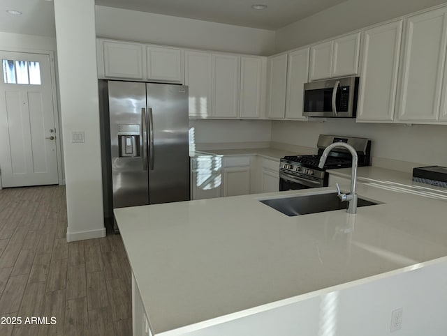 4330 N 94th Ave, Phoenix, AZ 85037 - kitchen with a peninsula, white cabinets, light wood-type flooring, and stainless steel appliances