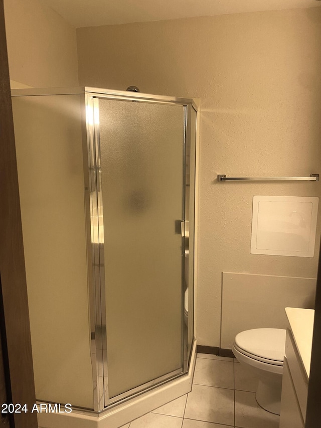 bathroom with toilet, vanity, tile patterned floors, and a shower with door