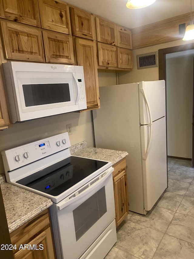 kitchen featuring light stone countertops and white appliances