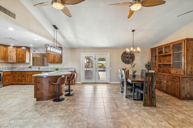 kitchen with a kitchen bar, light stone counters, vaulted ceiling, decorative light fixtures, and a center island