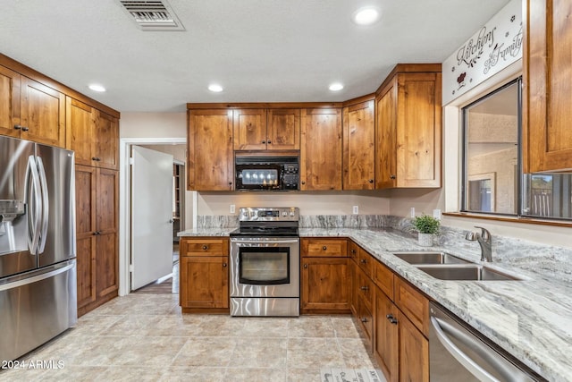 kitchen featuring light stone countertops, sink, a textured ceiling, and appliances with stainless steel finishes