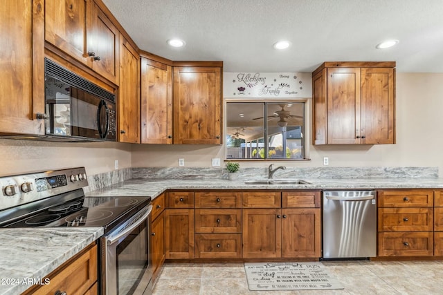 kitchen with sink, light stone countertops, a textured ceiling, light tile patterned floors, and stainless steel appliances