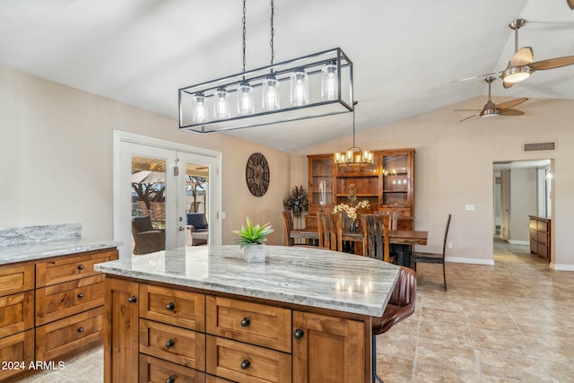 kitchen featuring a center island, lofted ceiling, french doors, ceiling fan with notable chandelier, and light stone counters