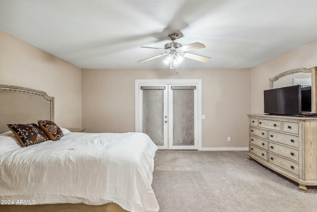 bedroom with ceiling fan, french doors, and light carpet