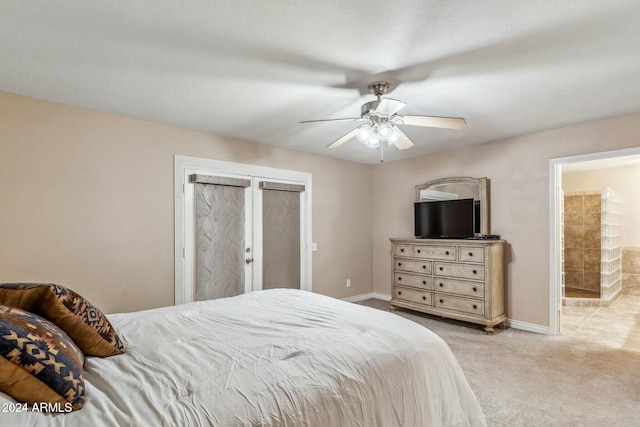 bedroom featuring ensuite bathroom, ceiling fan, and light carpet