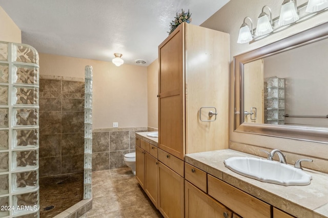 bathroom featuring a tile shower, tile patterned floors, a textured ceiling, toilet, and vanity