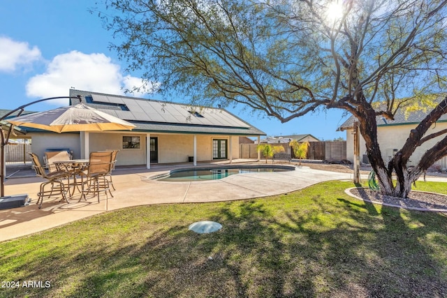 back of property featuring solar panels, a patio area, a fenced in pool, and a yard