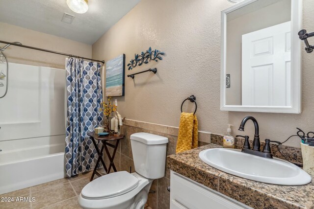 full bathroom with shower / bath combo, tile patterned flooring, a textured ceiling, toilet, and vanity