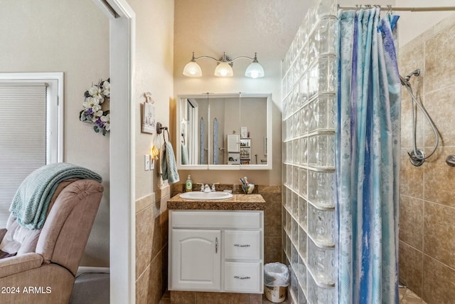 bathroom featuring tiled shower, vanity, and tile walls