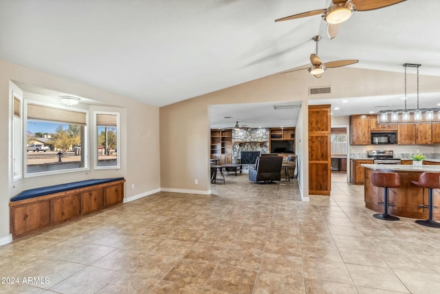 tiled living room featuring ceiling fan, a fireplace, and lofted ceiling