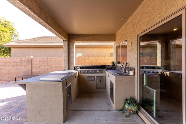 view of patio with an outdoor kitchen, sink, and grilling area