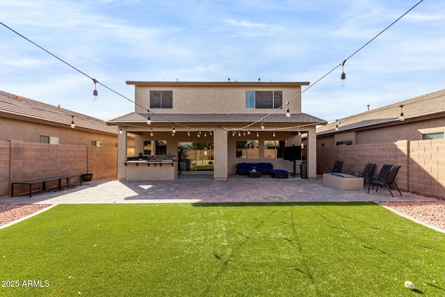 back of house with a lawn, a patio area, an outdoor living space, and an outdoor kitchen