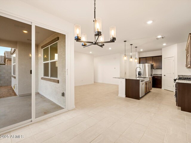 3550 N Camden Dr, Florence, AZ 85132 - kitchen featuring appliances with stainless steel finishes, a chandelier, dark brown cabinets, open floor plan, and an island with sink