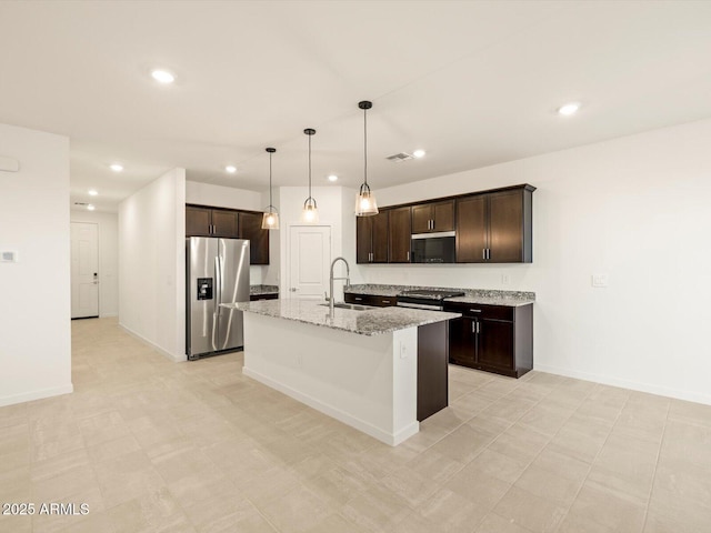 3550 N Camden Dr, Florence, AZ 85132 - kitchen with appliances with stainless steel finishes, dark brown cabinetry, recessed lighting, an island with sink, and light stone counters