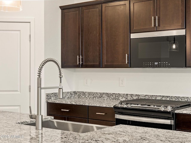 3550 N Camden Dr, Florence, AZ 85132 - kitchen featuring stainless steel microwave, black gas range oven, dark brown cabinetry, and light stone counters