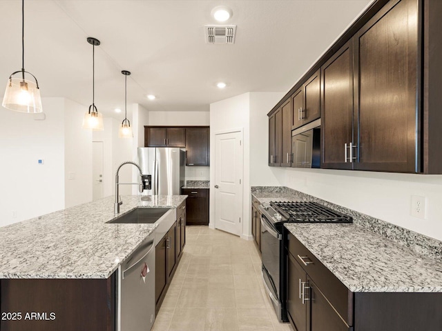 3550 N Camden Dr, Florence, AZ 85132 - kitchen with stainless steel appliances, dark brown cabinets, light stone countertops, recessed lighting, and pendant lighting