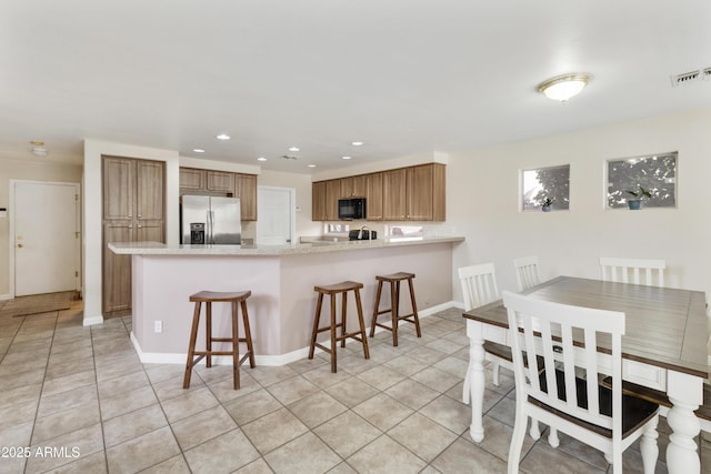 1072 W Windhaven Ave, Gilbert, AZ 85233 - kitchen with stainless steel fridge, black microwave, a peninsula, light tile patterned flooring, and recessed lighting