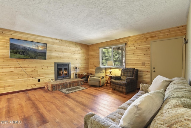 3017 Larson Loop, Forest Lakes, AZ 85931 - living area with wood finished floors, wood walls, a textured ceiling, and a glass covered fireplace