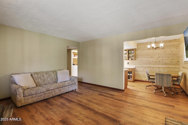3017 Larson Loop, Forest Lakes, AZ 85931 - living room with light wood-type flooring, a chandelier, wood walls, baseboards, and a textured ceiling