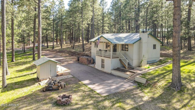 3017 Larson Loop, Forest Lakes, AZ 85931 - view of front of house with stairway, a storage shed, a fire pit, metal roof, and covered porch
