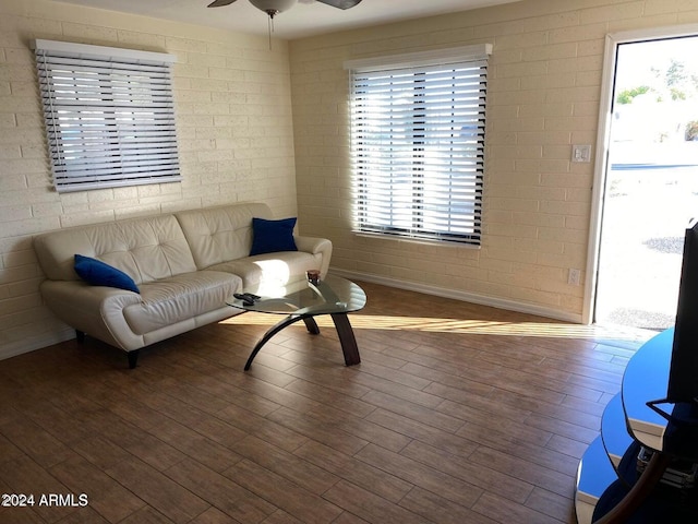 living room with hardwood / wood-style floors, ceiling fan, and brick wall