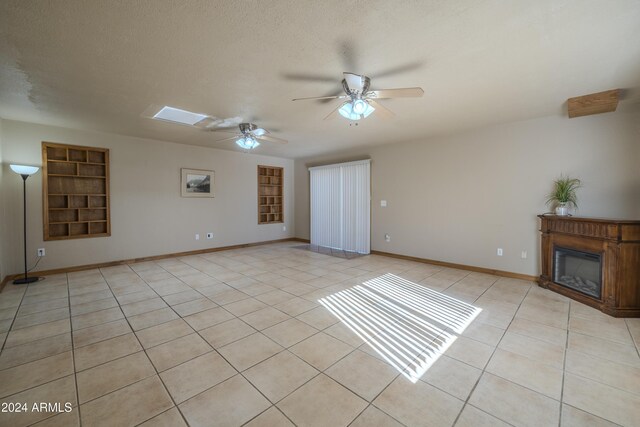 unfurnished living room featuring built in shelves, light tile patterned floors, and a textured ceiling