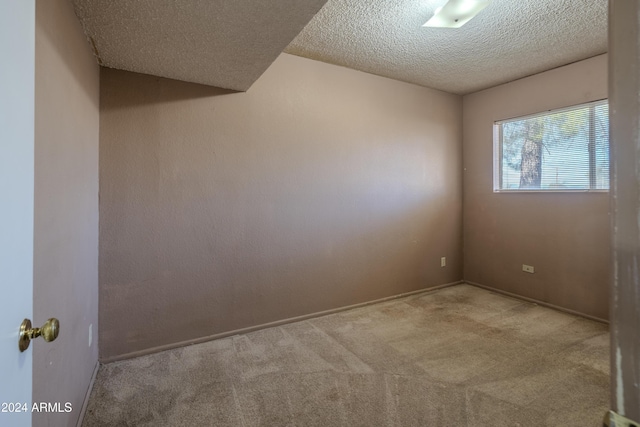 carpeted empty room with a textured ceiling