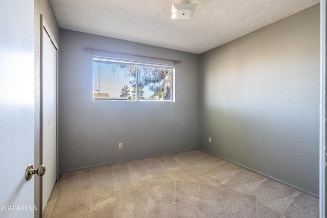 unfurnished room with a textured ceiling and light carpet