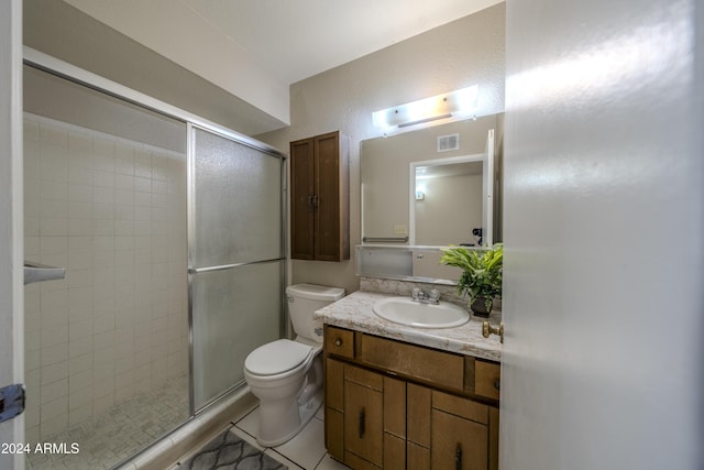 bathroom with toilet, vanity, tile patterned floors, and a shower with door