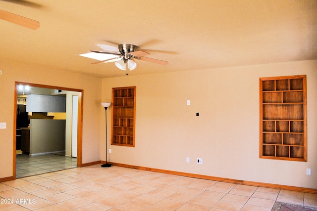 tiled spare room featuring built in shelves and ceiling fan