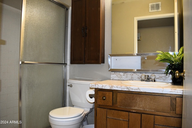 bathroom featuring toilet, an enclosed shower, and vanity