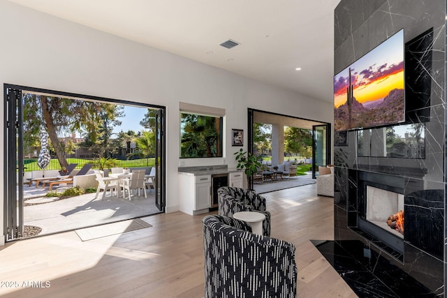 living room featuring a fireplace, light wood-type flooring, and wine cooler