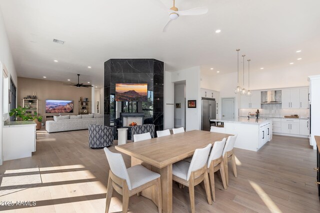 dining space featuring a premium fireplace, sink, and light hardwood / wood-style flooring